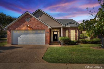 View of front facade with a lawn and a garage | Image 1