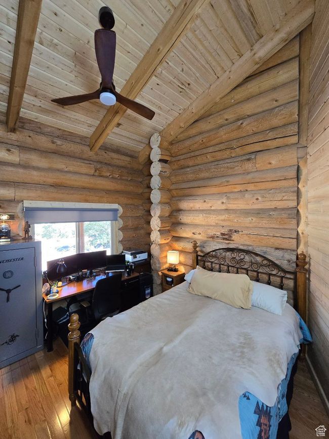 Bedroom with hardwood / wood-style floors, lofted ceiling with beams, ceiling fan, wooden ceiling, and rustic walls | Image 71