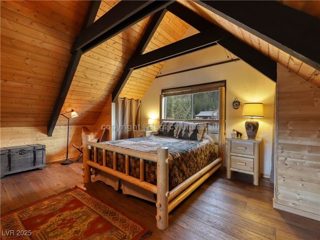 Bedroom featuring wooden ceiling, vaulted ceiling with beams, wood walls, and hardwood / wood-style floors | Image 25
