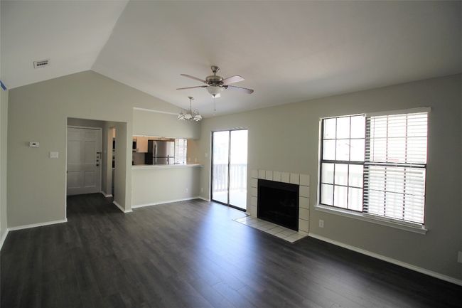 Unfurnished living room featuring a ceiling fan, lofted ceiling, a tile fireplace, and dark wood-style floors | Image 9
