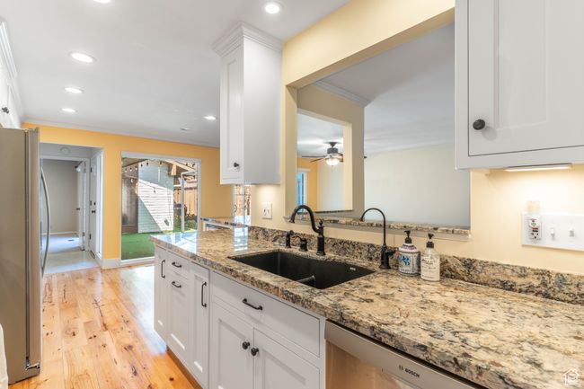Kitchen with light stone counters, crown molding, a sink, stainless steel appliances, and white cabinets | Image 10