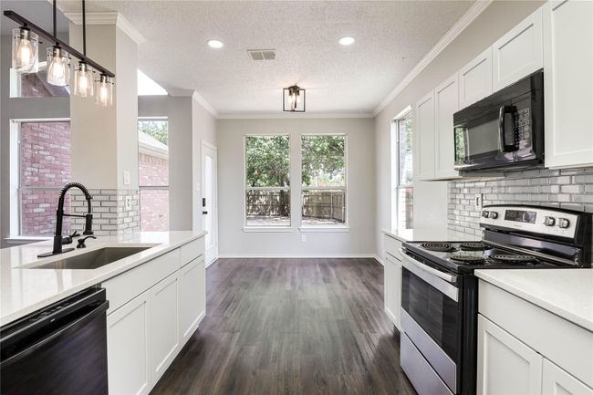 Kitchen featuring black appliances, a sink, a textured ceiling, light countertops, and tasteful backsplash | Image 15