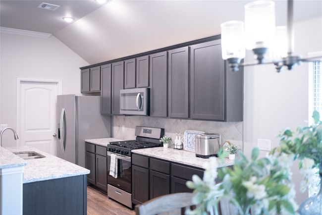 Kitchen with a sink, stainless steel appliances, tasteful backsplash, visible vents, and vaulted ceiling | Image 9
