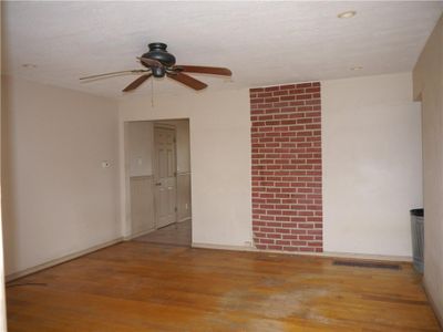 Empty room with a textured ceiling, light wood-type flooring, and ceiling fan | Image 3