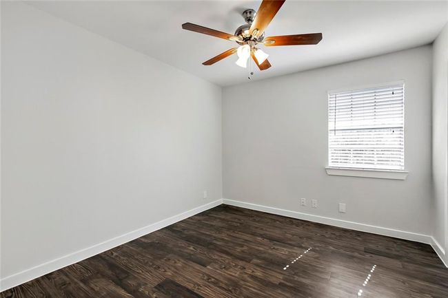 Empty room with dark wood-style flooring, baseboards, and a ceiling fan | Image 5