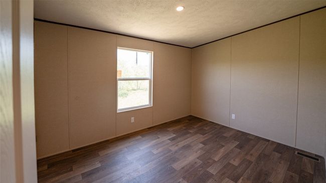 Unfurnished room featuring dark wood-style floors, a decorative wall, and a textured ceiling | Image 21