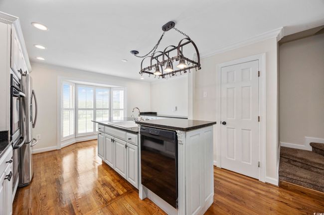 Kitchen with black dishwasher, a sink, ornamental molding, a chandelier, and a kitchen island with sink | Image 18