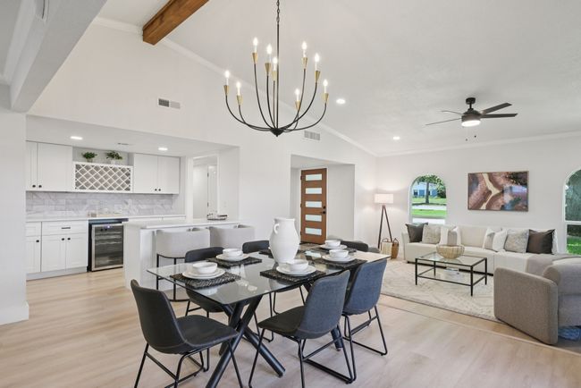 Dining room with wine cooler, light wood-style flooring, bar with sink, ornamental molding, and recessed lighting | Image 16