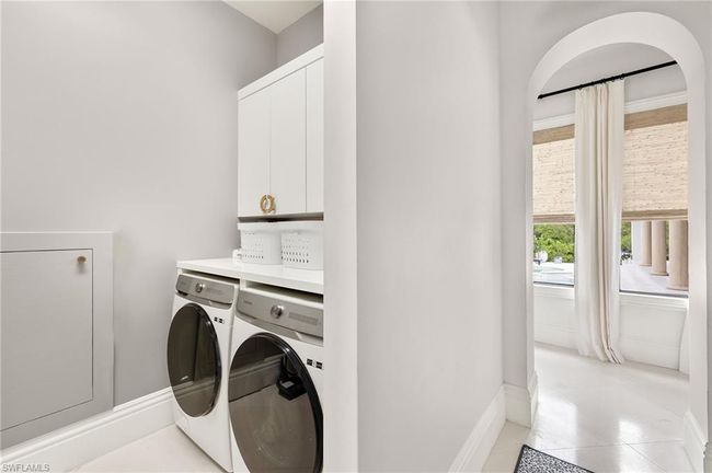 Laundry room with baseboards, cabinet space, light tile patterned flooring, and washing machine and clothes dryer | Image 34