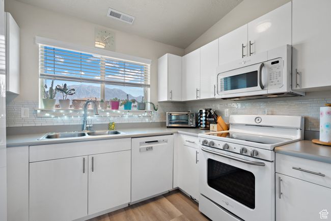 Kitchen with white appliances, decorative backsplash, and light countertops | Image 4