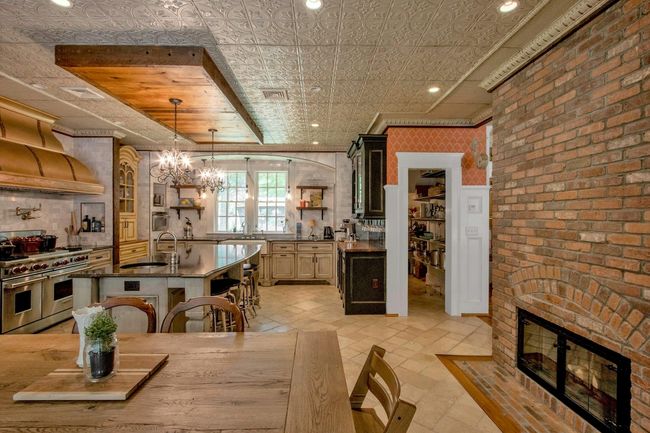 Kitchen featuring range with two ovens, open shelves, a sink, a breakfast bar, and dark countertops | Image 12