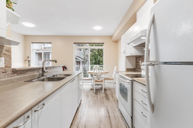 Kitchen with a sink, light wood-type flooring, white appliances, under cabinet range hood, and white cabinetry | Image 12