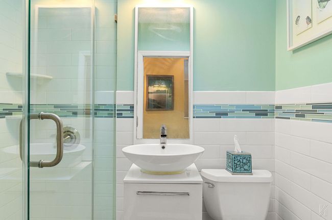 Full bathroom with toilet, tile walls, vanity, and a stall shower | Image 12