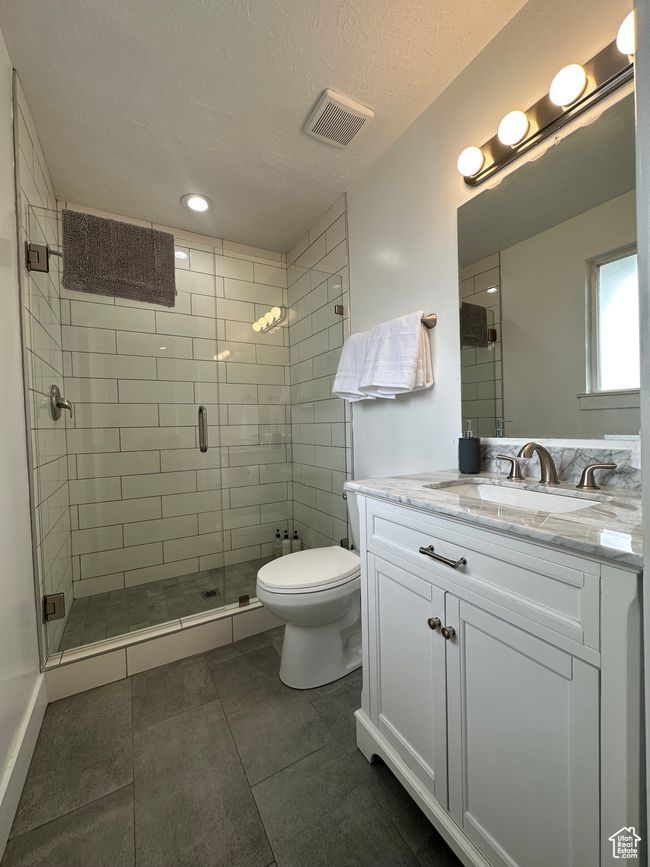 Bathroom featuring toilet, a shower stall, vanity, tile patterned flooring, and recessed lighting | Image 9