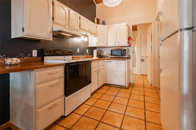 Kitchen with white cabinetry, under cabinet range hood, and white appliances | Image 6