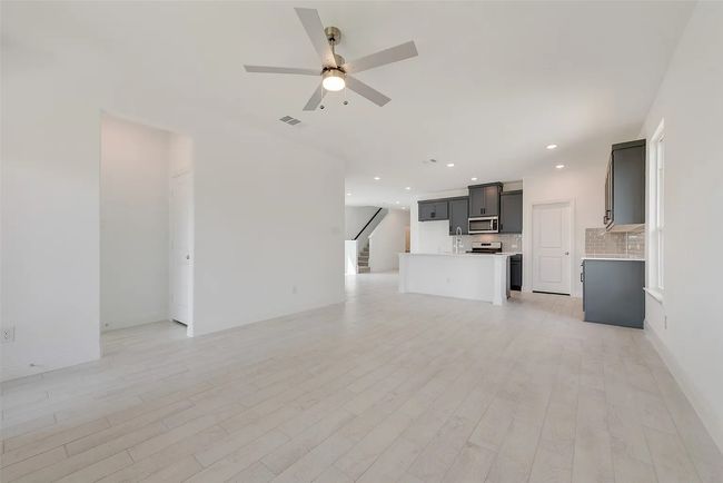 Unfurnished living room with ceiling fan, stairway, light wood-type flooring, recessed lighting, and baseboards | Image 7