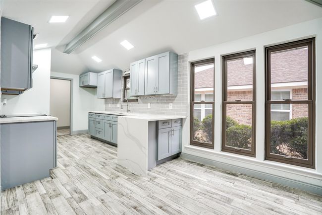 Kitchen featuring gray cabinets, light wood-style floors, a sink, and backsplash | Image 8