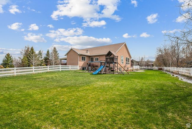 Back of house with stucco siding, a lawn, a fenced backyard, and a playground | Image 53