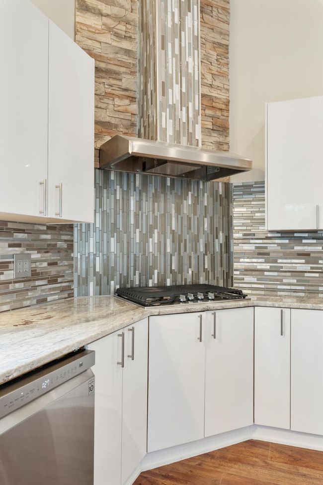 Intricate tile work all around with a gas cooktop and exhaust system | Image 14