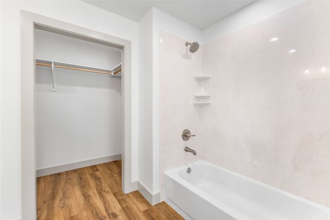 Bathroom with tub / shower combination, wood finished floors, a spacious closet, and baseboards | Image 20