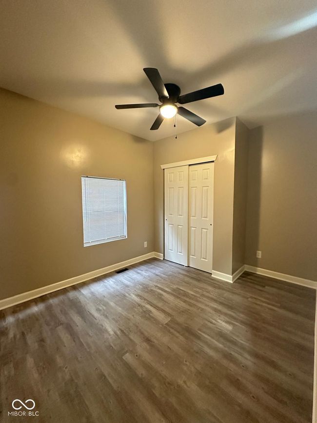 Unit 1 - unfurnished bedroom with dark wood-style floors, a closet, and ceiling fan | Image 12