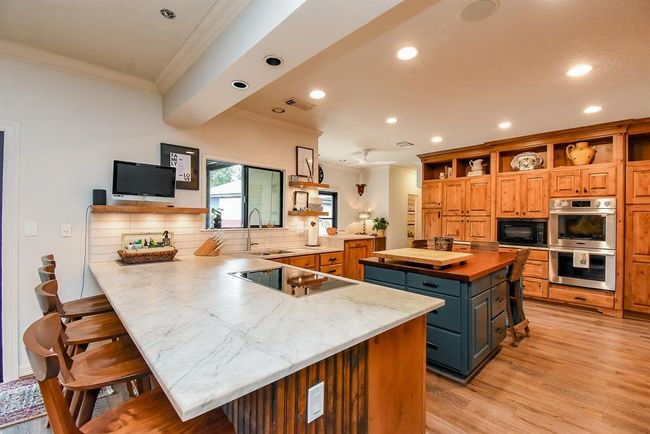 This kitchen has it all! Galley kitchen sink, Quartzite counters, induction cooktop offers easy cleaning and instant temperature control, double ovens (2024), raised dishwasher (easy on your back), appliance garage, built in refrigerator, and ice maker. Not to mention the large kitchen island! | Image 14