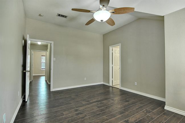 Empty room with vaulted ceiling, dark hardwood / wood-style floors, and ceiling fan | Image 13