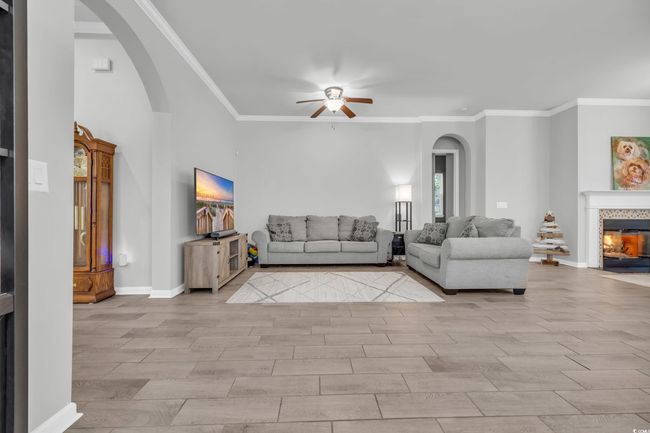 Unfurnished living room featuring arched walkways, a tile fireplace, wood finish floors, and a ceiling fan | Image 15