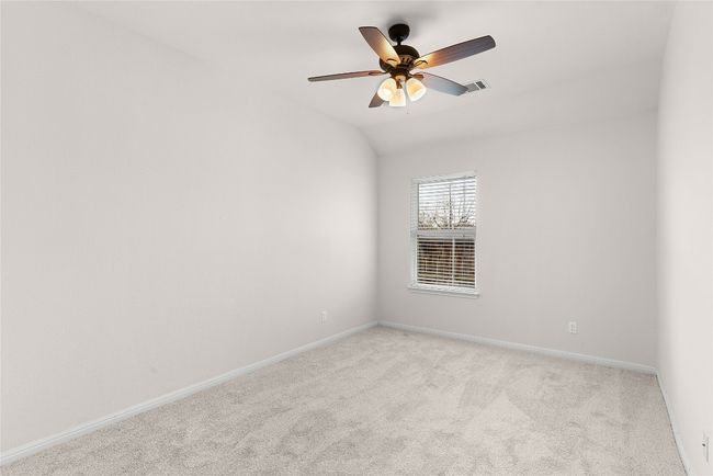 Empty room featuring a ceiling fan, baseboards, visible vents, vaulted ceiling, and light carpet | Image 17