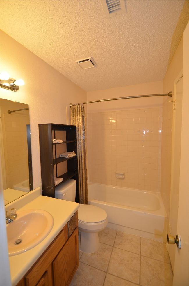 Bathroom featuring tile patterned flooring, vanity, toilet, shower / bathtub combination with curtain, and a textured ceiling | Image 8
