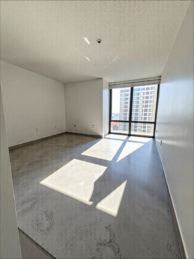 Unfurnished room featuring finished concrete flooring, a textured ceiling, and baseboards | Image 5