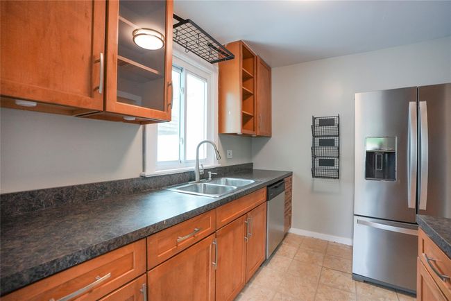 Kitchen featuring brown cabinetry, baseboards, stainless steel appliances, and a sink | Image 11