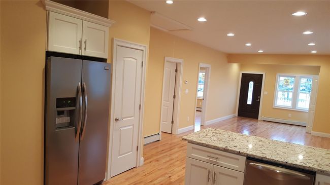 Kitchen with stainless steel appliances, a baseboard radiator, a healthy amount of sunlight, and white cabinetry | Image 8