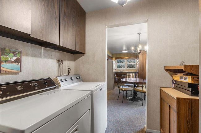 Laundry area with carpet floors, cabinet space, a chandelier, and washer and clothes dryer | Image 12