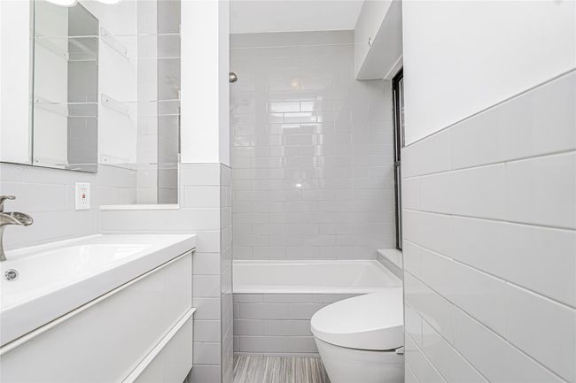 Bathroom with tile walls, vanity, and shower combination | Image 17