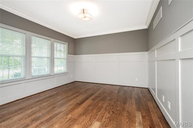 Front den with dark wood flooring, a decorative wall, and ornamental molding | Image 8