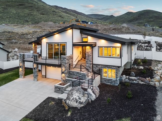 Contemporary home featuring a garage, a mountain view, driveway, stone siding, and fence | Image 70