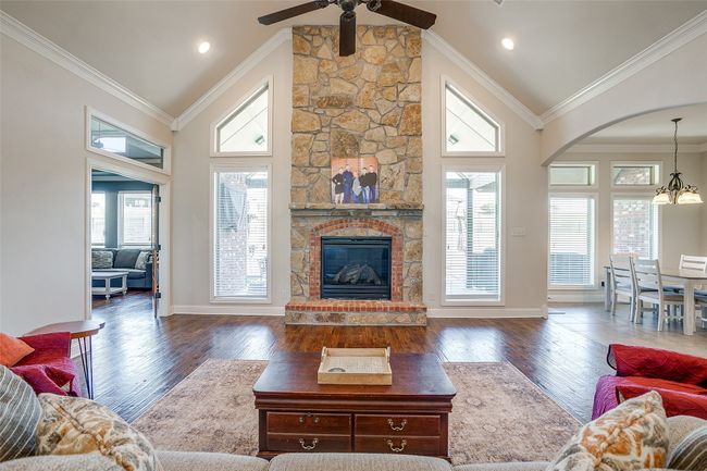 Living room featuring dark wood-type flooring, ceiling fan with notable chandelier, high vaulted ceiling, and ornamental molding | Image 7