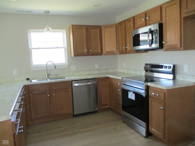 kitchen featuring brown cabinetry, appliances with stainless steel finishes, and a sink | Image 8