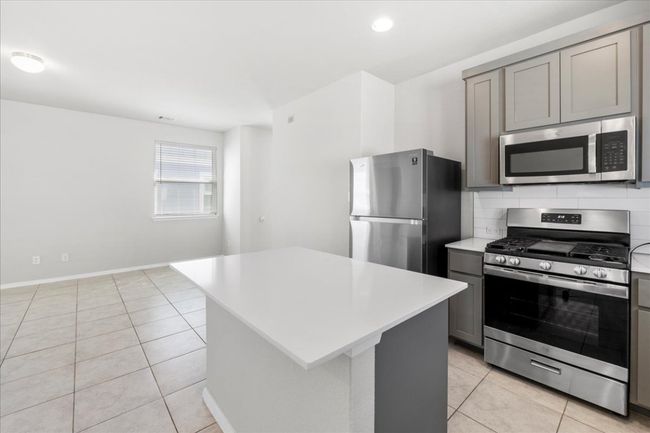 Kitchen featuring tasteful backsplash, light tile patterned flooring, light countertops, stainless steel appliances, and gray cabinetry | Image 11