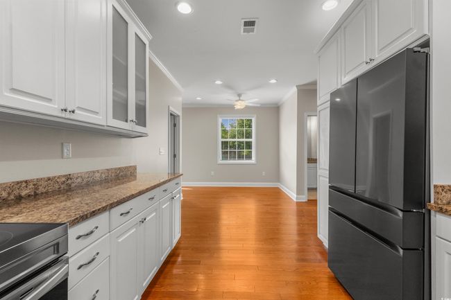 Kitchen with freestanding refrigerator, ornamental molding, white cabinetry, ceiling fan, and light wood-type flooring | Image 13