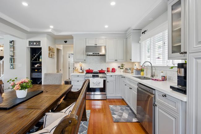 Kitchen featuring under cabinet range hood, a sink, light wood-style floors, appliances with stainless steel finishes, and light countertops | Image 10