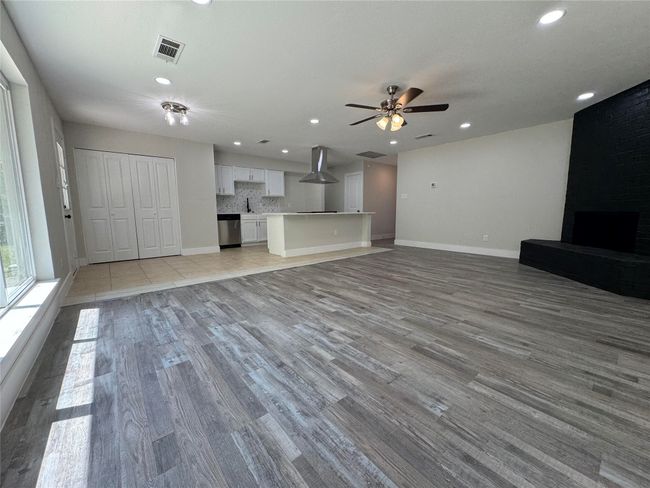 Unfurnished living room featuring ceiling fan, a fireplace, light wood-style flooring, visible vents, and baseboards | Image 6