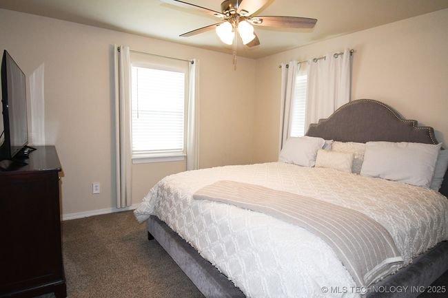Carpeted bedroom with multiple windows, baseboards, and ceiling fan | Image 19