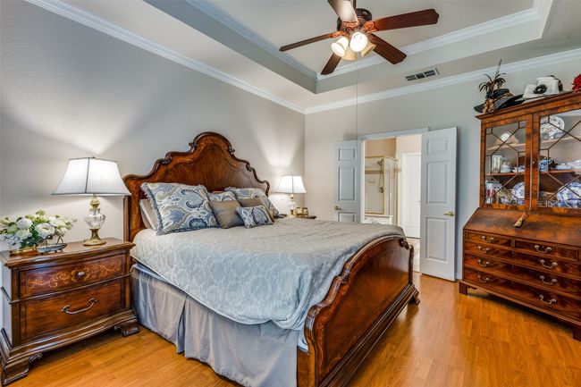 Bedroom featuring a tray ceiling, light wood-style flooring, ornamental molding, and a ceiling fan | Image 18