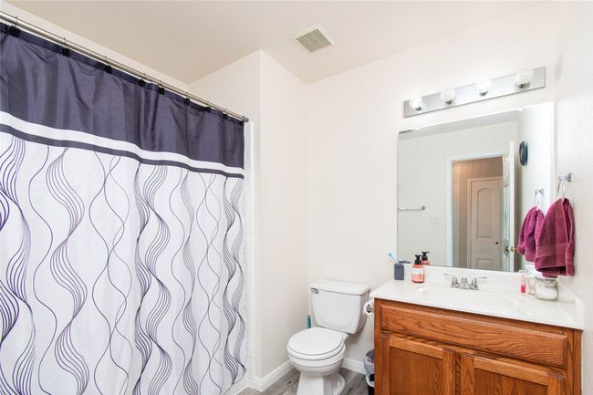 Bathroom with visible vents, toilet, vanity, and a shower with curtain | Image 16