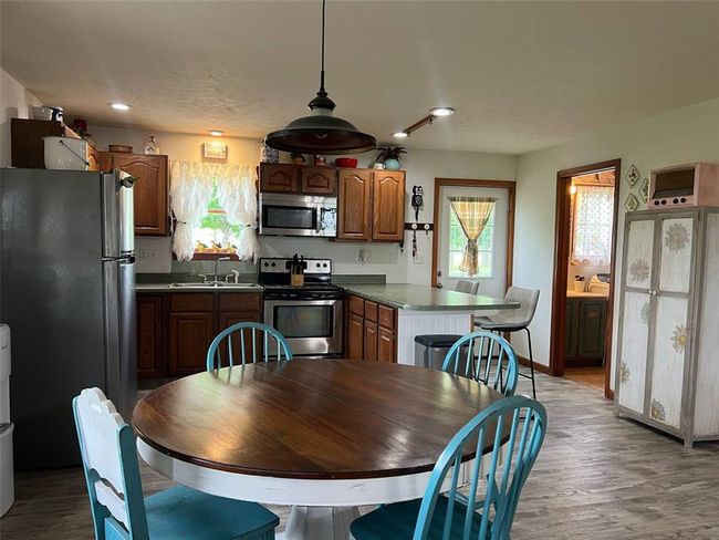 Kitchen with stainless steel appliances, a sink, wood finished floors, dark countertops, and a peninsula | Image 5