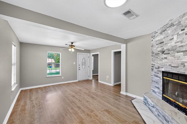 Unfurnished living room featuring a fireplace, wood finished floors, and ceiling fan | Image 23