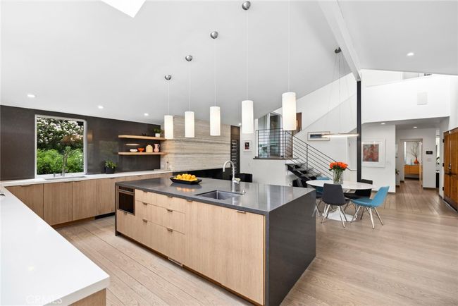 Thermador, Miele, Bosch and Dacor appliances, including a built-in cabinet-matched refrigerator, ensure ease of meal prep in the kitchen, which joins an intimate fireplace-warmed living area, a dining space, and access to outdoor dining on the deck. | Image 13