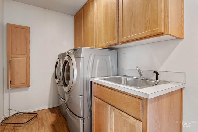 Laundry area featuring cabinet space, independent washer and dryer, and light wood-type flooring | Image 14